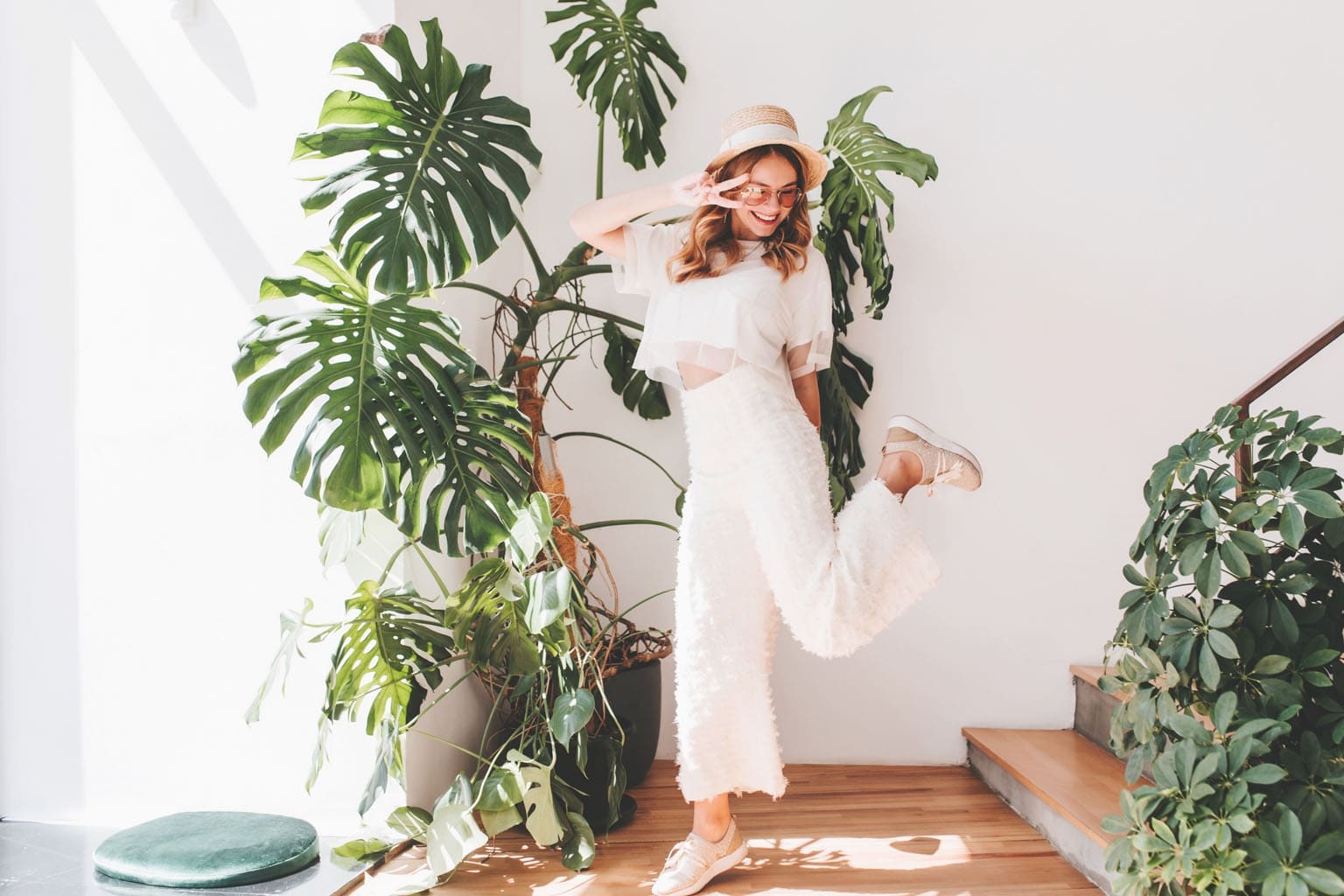 Femme souriante et dynamique dans un intérieur lumineux entouré de plantes, symbole de renouveau et de bien-être au printemps